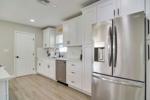 Una cocina moderna con armarios blancos, electrodomésticos de acero inoxidable y lavavajillas.