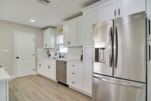 Una cocina moderna con armarios blancos, electrodomésticos de acero inoxidable y lavavajillas.