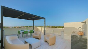 A rooftop terrace with a covered seating area, a dining table, and chairs. - Bonsai 1BR Suite- Yutori 306 (Noord)