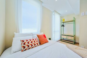 A bedroom with a bed, pillows, a green metal shelf, and a window. - Bonsai 2BR Retreat-Flow 201 (Noord)