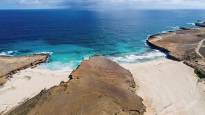Een kustlandschap met een zandstrand en rotskliffen die uitkijken over de oceaan.