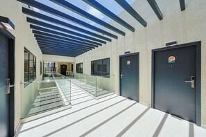 A modern building with a covered walkway, glass railings, and doors with stickers. - Bonsai 2BR Retreat-Flow 201 (Noord)
