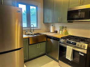 A kitchen with stainless steel appliances, a window, and a microwave.