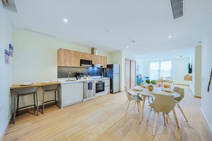 Une cuisine moderne avec un coin repas, des meubles en bois et une vue sur le salon.
