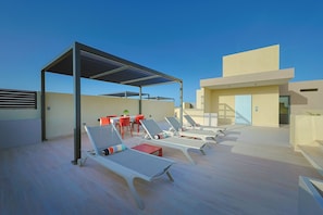 A rooftop terrace with sun loungers, a table, and chairs. - Bonsai 2BR Retreat-Balance 211 (Noord)