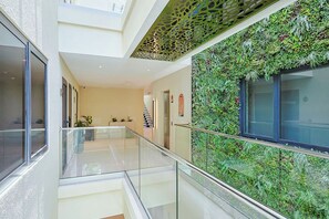 A modern interior with a glass railing, a staircase, and a wall covered in greenery. - Bonsai 2BR Retreat-Balance 211 (Noord)
