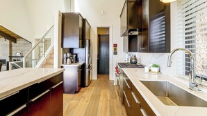 Una cocina moderna con electrodomésticos de acero inoxidable, encimera de mármol y suelo de madera.