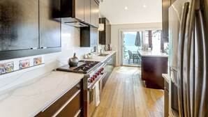 Una cocina moderna con electrodomésticos de acero inoxidable, encimera de mármol y vistas al exterior.
