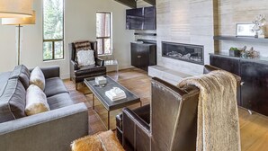 Una sala de estar moderna con chimenea, muebles de cuero y televisión.
