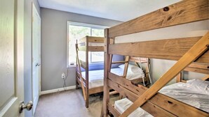 Une chambre avec un lit superposé, une fenêtre, une porte et un luminaire au plafond.