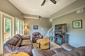 A living room with a sectional sofa, a leather armchair, a round coffee table, a television, and a fireplace. - Amazing views, hot tub, foosball! (McGaheysville)