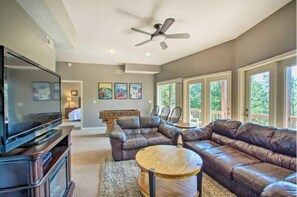 A living room with a flat-screen TV, leather sofas, a wooden coffee table, and a ceiling fan. - Amazing Views! Hot tub, Dog Friendy bonus Loft! (McGaheysville)