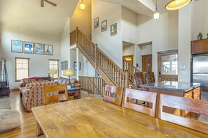 A spacious living area with a wooden staircase, a dining table, and a kitchen area. - Hike, Bike & Ski! Rendezvous Cabin w/ Mtn Views (Fraser)