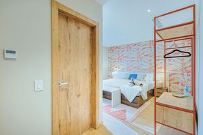 Ein Hotelzimmer mit Holztür, einem Bett mit weißer Bettwäsche, einem Nachttisch und einem Spiegel mit Holzrahmen.