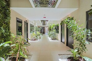 Corredor com plantas, portas e teto com padrão decorativo.