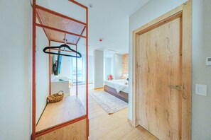 Un couloir menant à une chambre dotée d’une porte en bois, d’un porte-manteau et d’un petit panier.