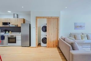 Um espaço compacto com cozinha compacta, máquina de lavar e sofá.