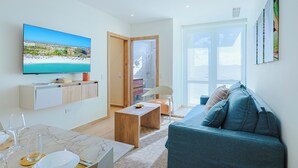 Un soggiorno moderno con televisione, un divano e un'area pranzo con tavolo e sedie.