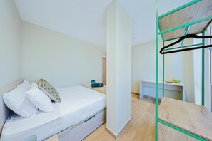 A bedroom with a bed, a bedside table, a hanging light, and a mirror with a wooden frame. - Bonsai 3BR Retreat Grand 207 (Noord)
