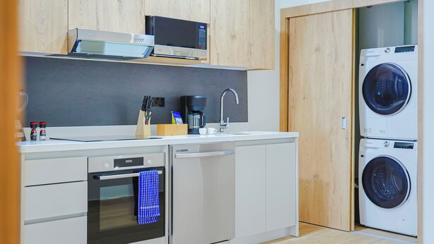 Una cucina compatta con forno a microonde, macchina per il caffè e lavatrice integrata.