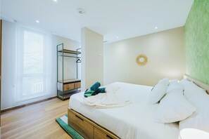 A bedroom with a bed, a wardrobe, a window, and a wall clock. - Bonsai 3BR Retreat Grand 207 (Noord)