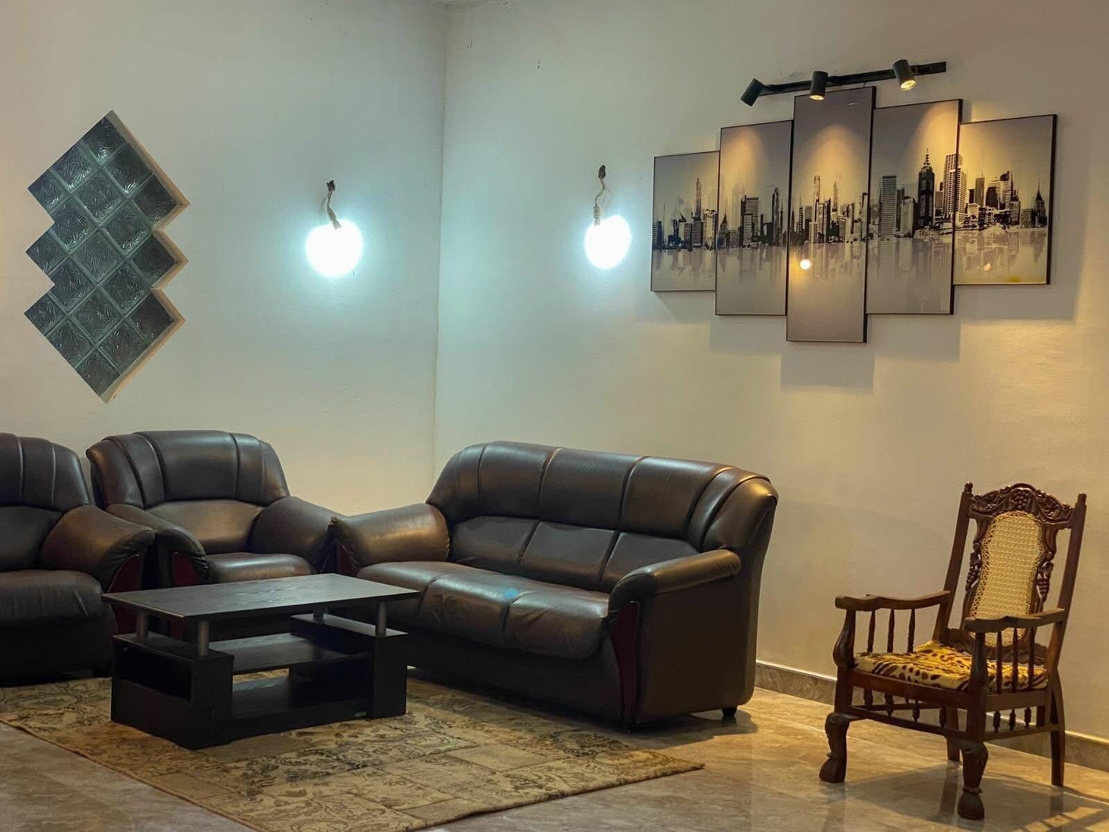 Una sala de estar con un sofá modular, una mesa de centro, un tapete estampado y una obra de arte con un motivo urbano.