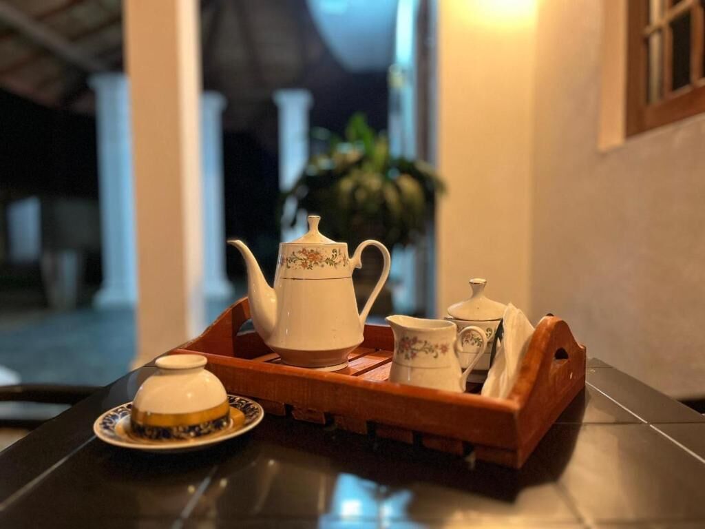Una bandeja con una tetera, una taza y un platito sobre una mesa.
