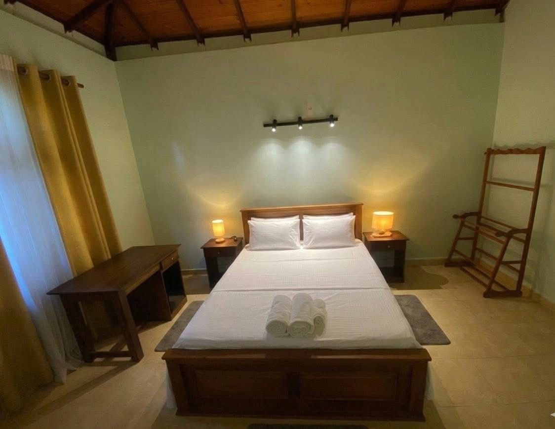 A single bed with a wooden frame, two bedside tables with lamps, a bench, and a wooden ladder against the wall.