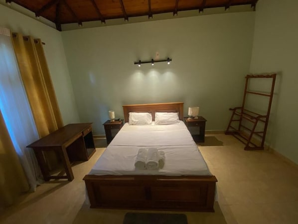 A bedroom with a wooden bed, bedside tables, a nightstand, a wall-mounted shelf, and a ladder.
