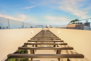 A modern staircase leading to a beach area with a clear sky. - Bonsai 3BR Retreat Grand 307 (Noord)