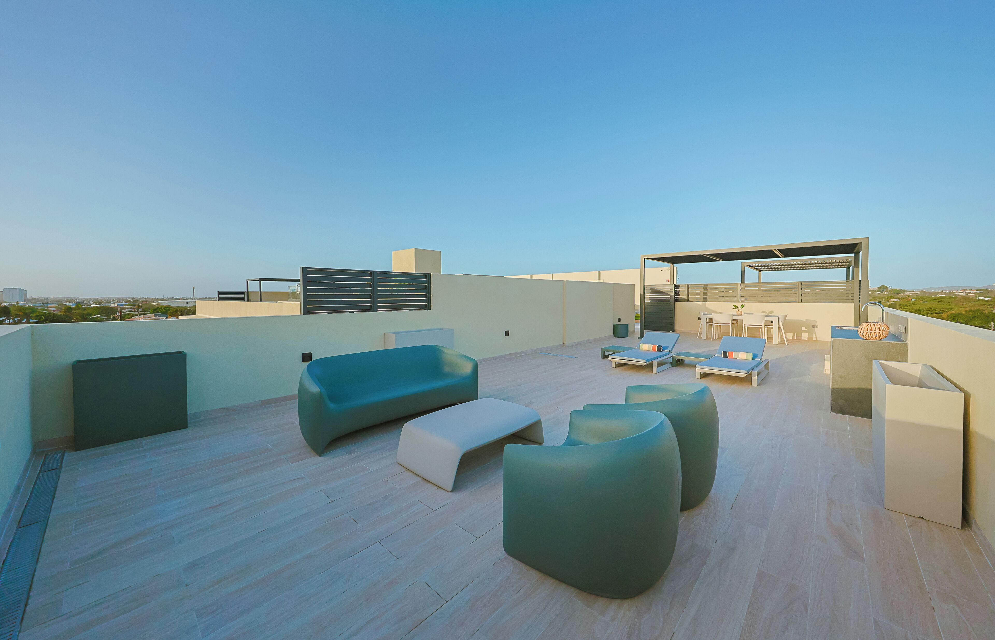A rooftop terrace with modern furniture, a pergola, and a view of the cityscape.