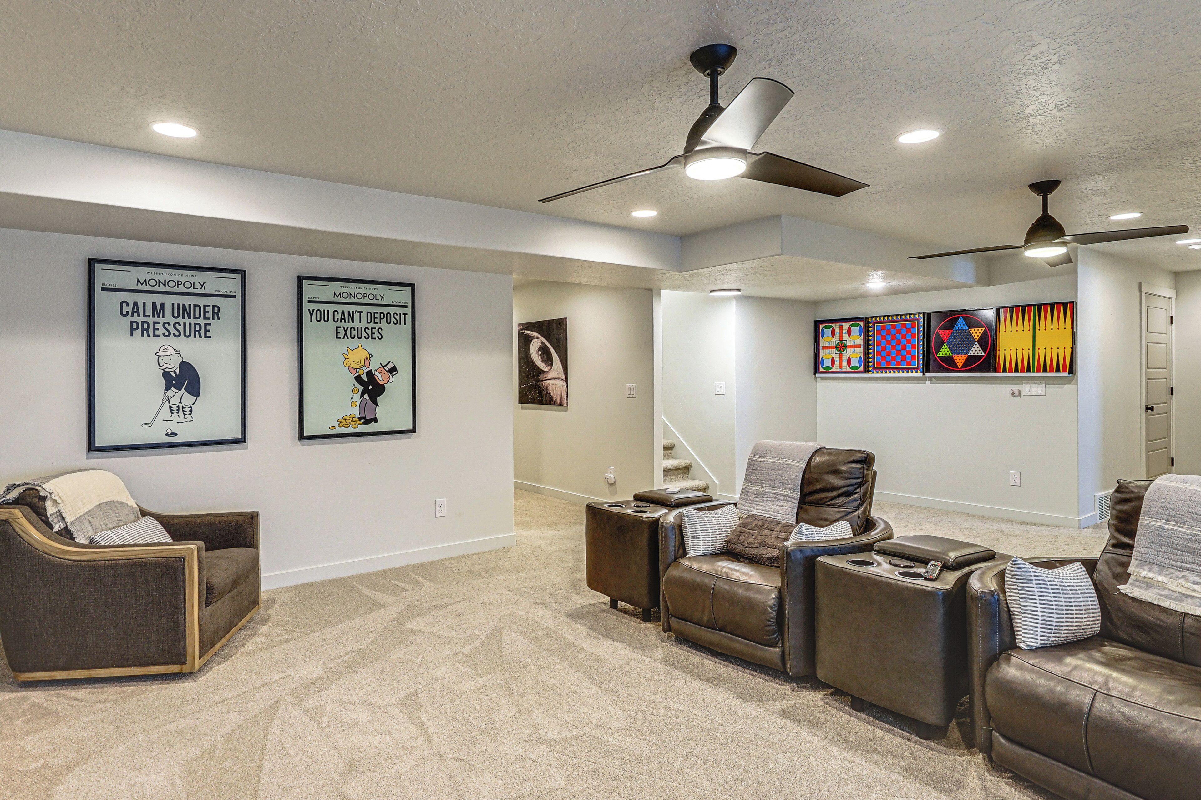 A home entertainment room with a ceiling fan, wall-mounted artwork, and leather recliners.