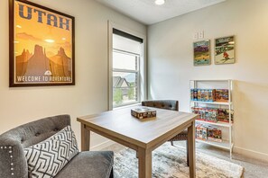 Ein Zimmer mit Esstisch, zwei Stühlen, einem Bücherregal und einem Fenster mit Blick.