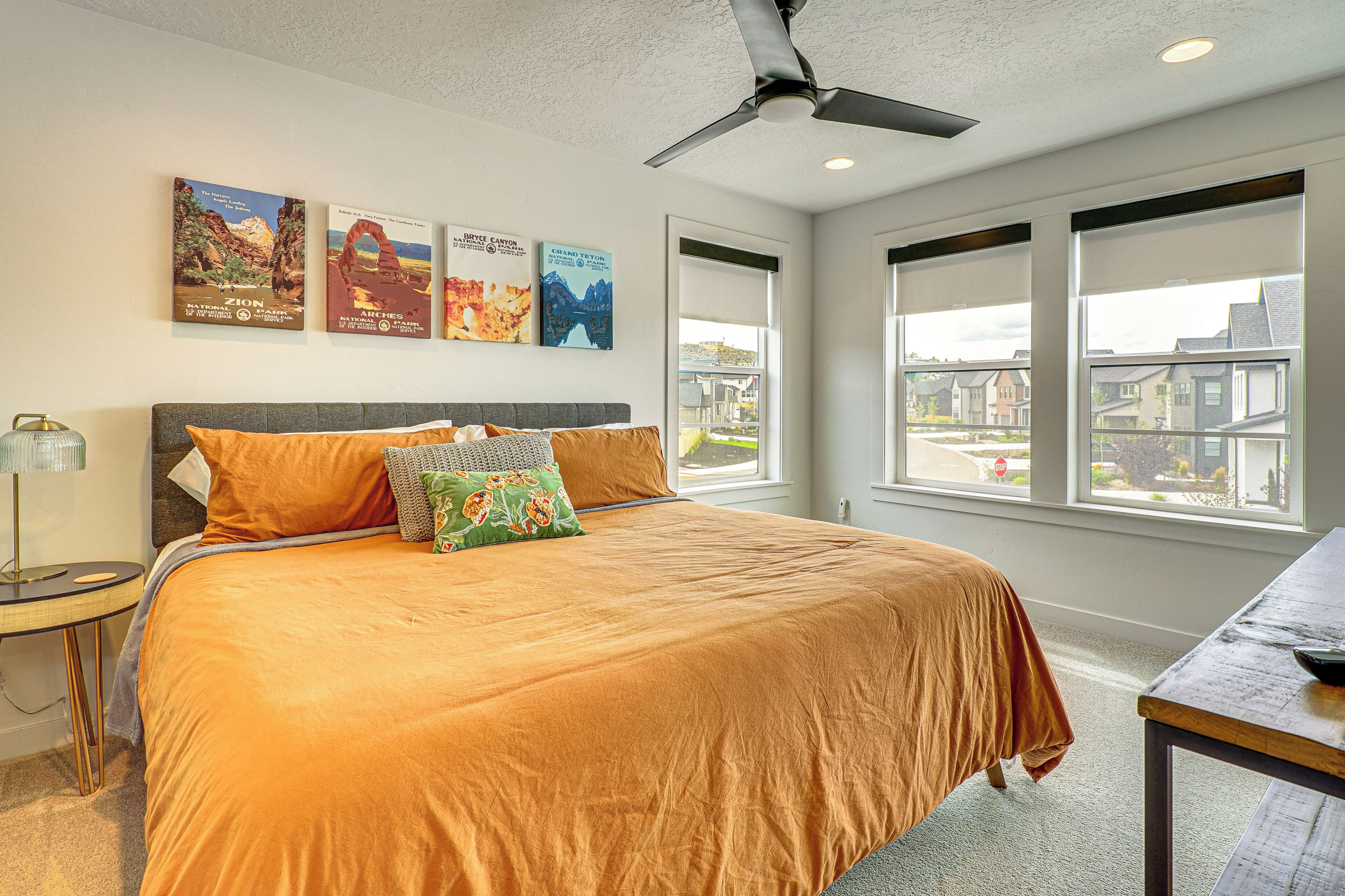 A bedroom with a large bed, a ceiling fan, and three wall-mounted posters.