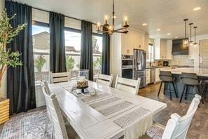 A modern kitchen with white cabinets, stainless steel appliances, and a dining area with a white table and chairs.