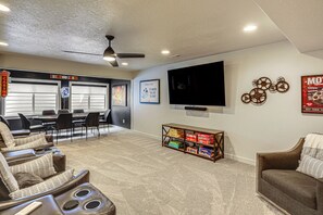 A room with a gaming area, a television, and a shelf with board games.
