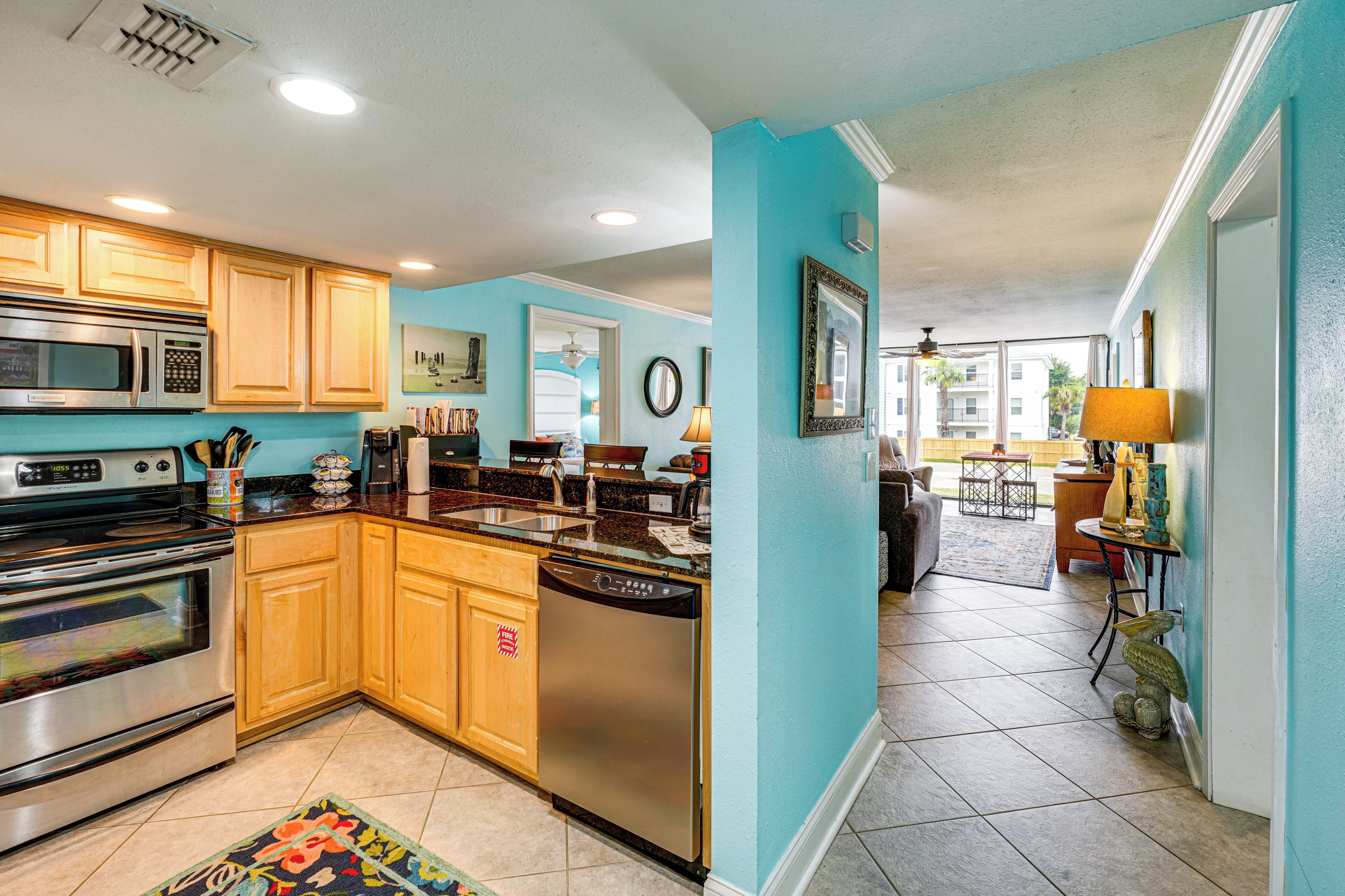 A modern kitchen with stainless steel appliances, wooden cabinets, and a teal accent wall.