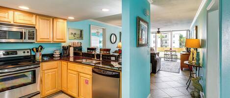 A modern kitchen with stainless steel appliances, wooden cabinets, and a teal accent wall.