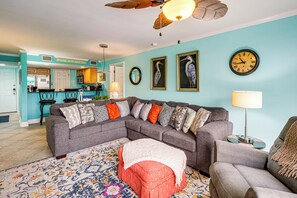 Ein Wohnzimmer mit Ecksofa, Couchtisch, Teppich mit Muster und Deckenventilator.