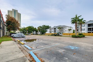 A parking lot with a covered car, a building with multiple floors, and a clear sky. - Walk to Beach! Biloxi Condo w/ Community Perks (Biloxi)