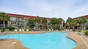 Ein Hotel mit Swimmingpool, Liegestühlen und Palmen.