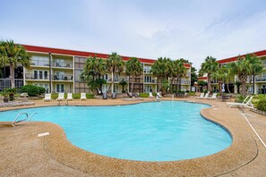 Ein Hotel mit Swimmingpool, Liegestühlen und Palmen.