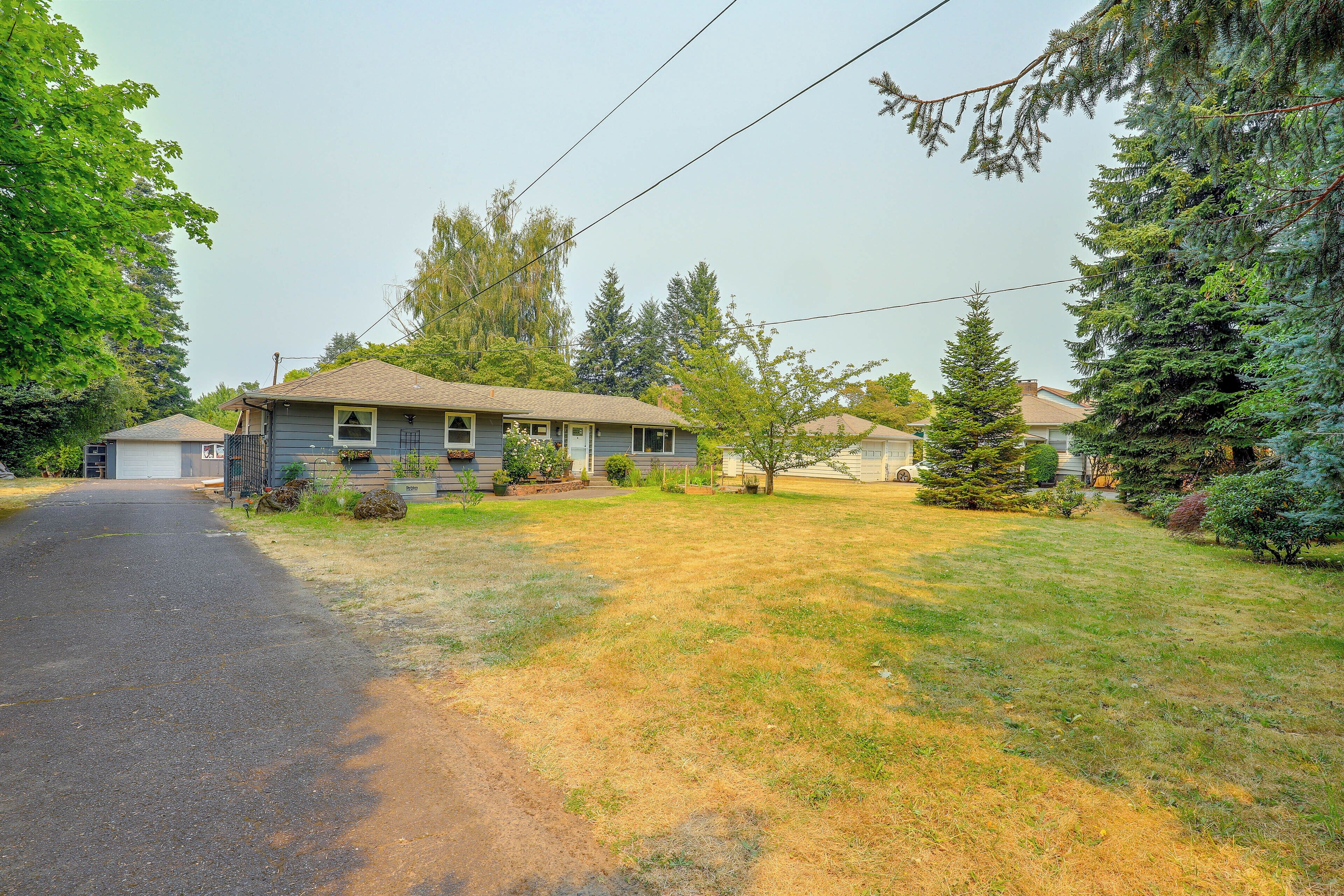 A residential house with a front yard, driveway, and surrounding trees.