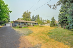 A residential house with a front yard, driveway, and surrounding trees.
