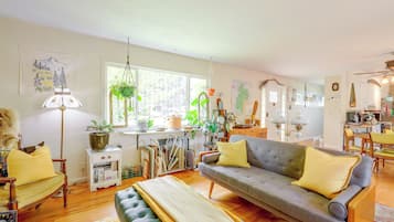 A cozy living room with a sofa, a coffee table, and various plants.