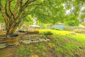 A garden with a large tree, stone pathway, and a wooden structure.