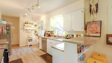 A kitchen with white cabinets, a central island, a refrigerator, and a dining area with a yellow chair.