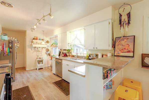 A kitchen with white cabinets, a central island, a refrigerator, and a dining area with a yellow chair.