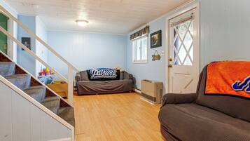 A living room with a staircase, a couch, a radiator, and a door with a window.