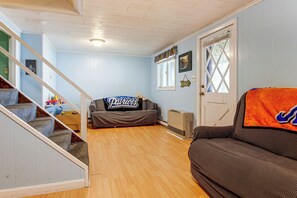 A living room with a staircase, a couch, a radiator, and a door with a window.